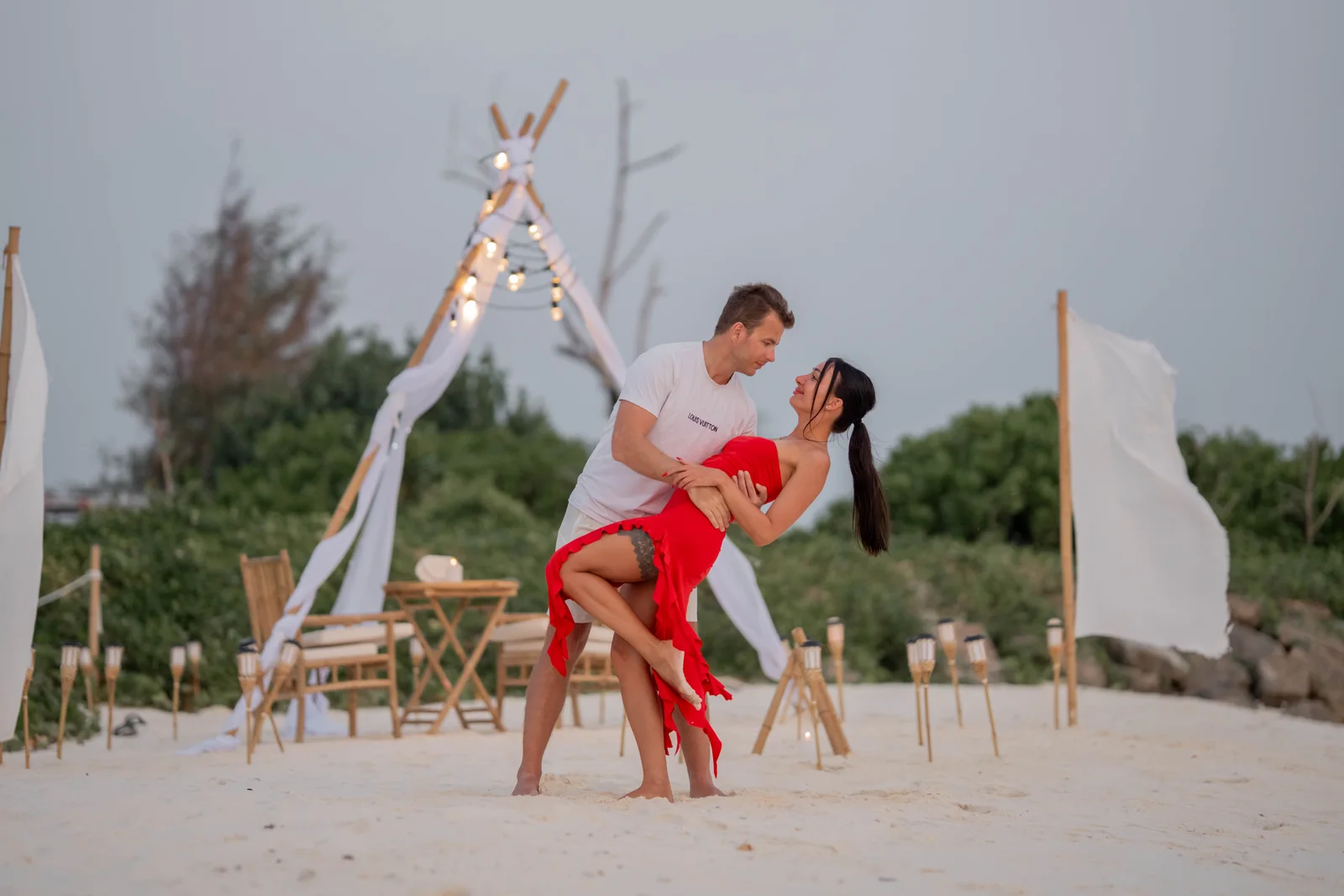 A couple celebrating beside a beach dining setup at Vahmaafushi